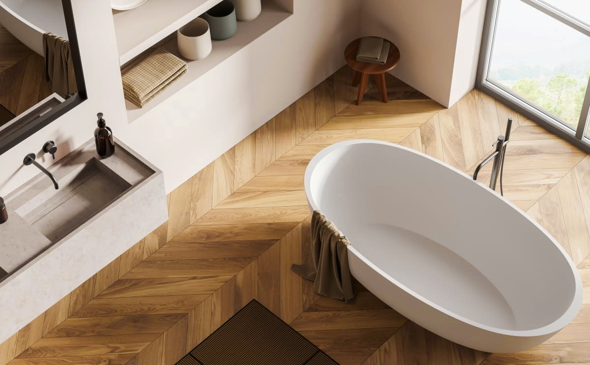 Modern mountain-style bathroom with freestanding white bathtub, wooden chevron flooring, and minimalist stone sink.